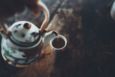 Cropped hand of person pouring tea in glass on table