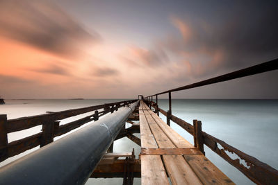 Pier over sea against sky during sunset