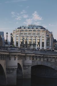 Arch bridge over river against buildings in city