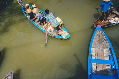 High angle view of people sitting on boat moored in river