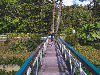 Rear view of man walking on footbridge