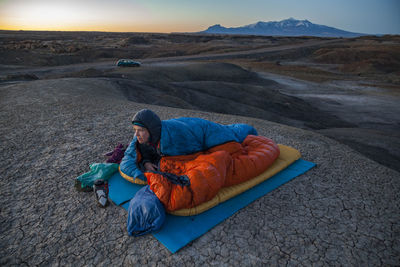 Woman watches sunrise from camp in factory butte badlands, utah