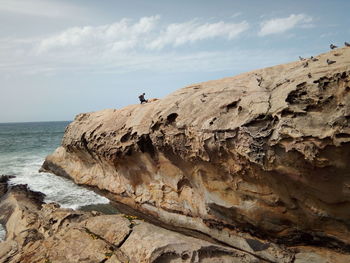 Rock formation on beach against sky