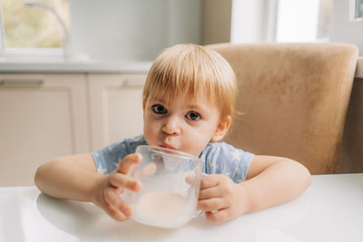 Portrait of happy little girl holding glass of milk, cute child drink fresh dairy product every day