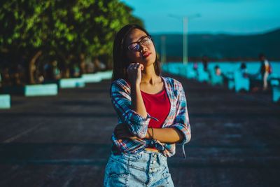 Beautiful young woman looking away while standing on land