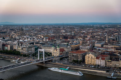 High angle view of bridge over river by buildings against sky during sunset