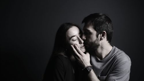 Portrait of young couple against black background