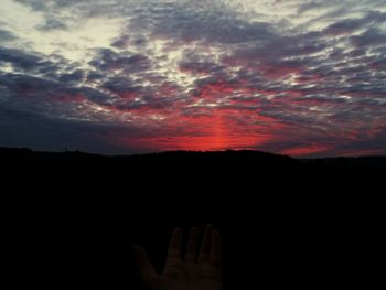 Silhouette hand against sky at sunset