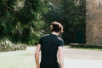 Rear view of woman standing against trees