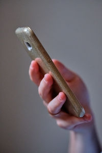 Close-up of hand holding cigarette over white background