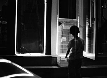 Rear view of boy looking through window