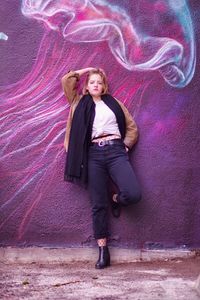 Portrait of woman standing against graffiti wall