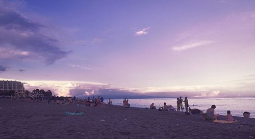 People on beach against sky during sunset