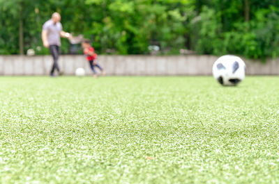 Man and son playing soccer on field