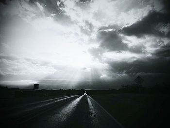 Road passing through landscape against cloudy sky