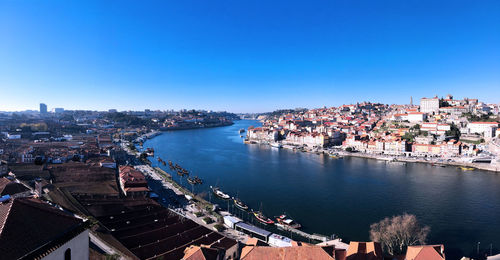 High angle view of river by buildings against blue sky