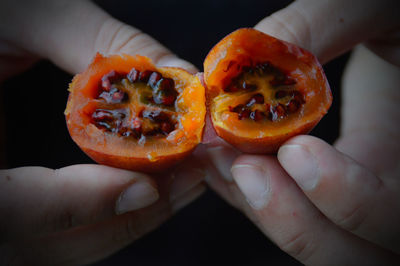 Close-up of hand holding orange fruit