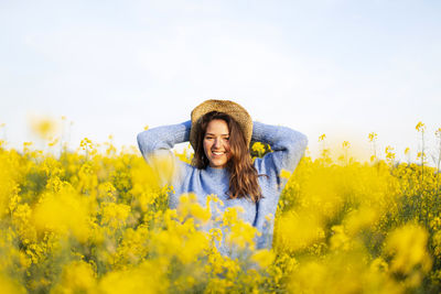 Portrait of smiling woman with yellow flowers in field