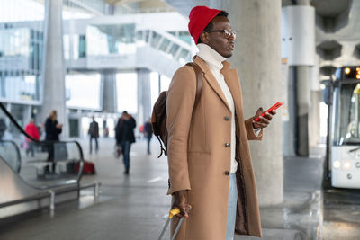 Man holding mobile phone standing at airport