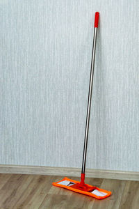 Red umbrella on wooden floor against wall at home