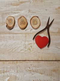 High angle view of dad alphabets by pliers and heart shape decoration on table