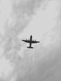 Low angle view of airplane flying against cloudy sky
