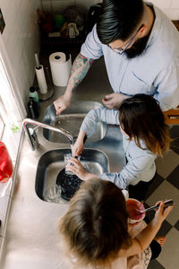 High angle view of father and daughter working while girl eating food in kitchen at home