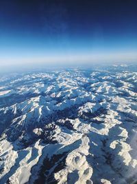 Aerial view of snowcapped mountain against blue sky