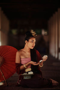 Teenager girl holding floral garland on floor