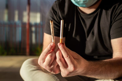 Midsection of man holding tobacco products