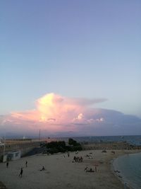 People on beach against sky during sunset