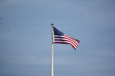 Low angle view of flag against blue sky