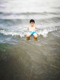 High angle view of boy enjoying in sea