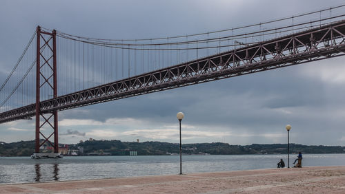 25 de abril bridge over tagus river against cloudy sky