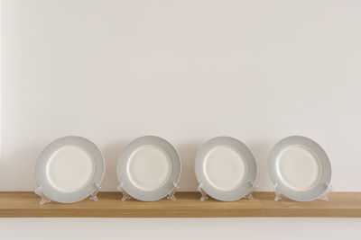 Table plates on stands stand on a wooden shelf in the dining room