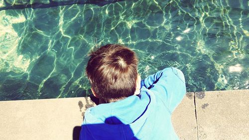 Rear view of boy standing in swimming pool