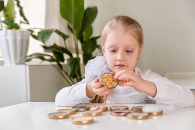 A girl student sits at a desk in the classroom and collects figures / puzzles / small toys