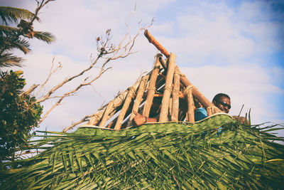 Low angle view of stack of logs against sky