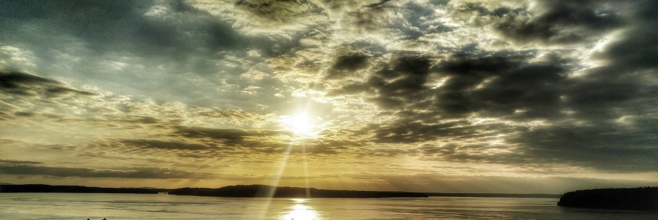 SUNLIGHT STREAMING THROUGH CLOUDS OVER WATER