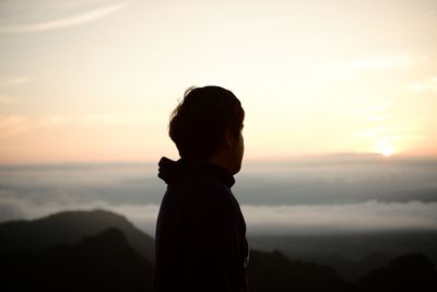 Silhouette man looking at mountains against sky during sunset