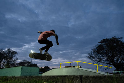 Young skateboarder doing a trick in skatepark during night