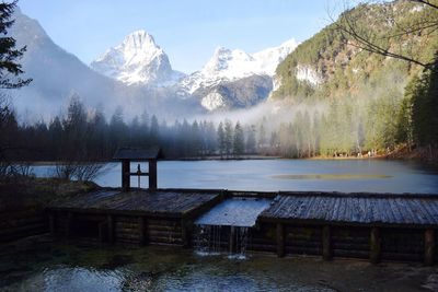 Scenic view of lake by snowcapped mountains against sky