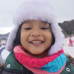 Portrait of cheerful girl wearing fur hat against sky during winter