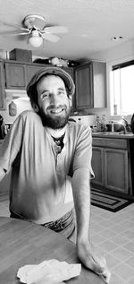 Portrait of man sitting standing n kitchen at home