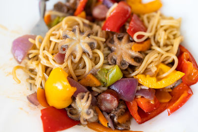 Spaghetti with octopus, tomatoes and assorted herbs - italian food - closeup