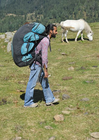 Side view of a male tourist walking on the mountain with carrying parachute backpack