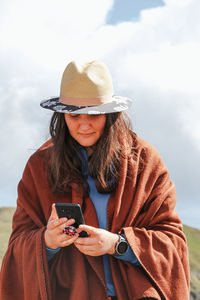 Portrait of woman wearing hat while standing on mobile phone