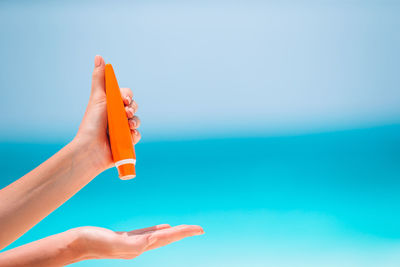 Midsection of woman hand on sea against sky