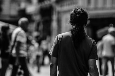 Rear view of man with ponytail standing on street