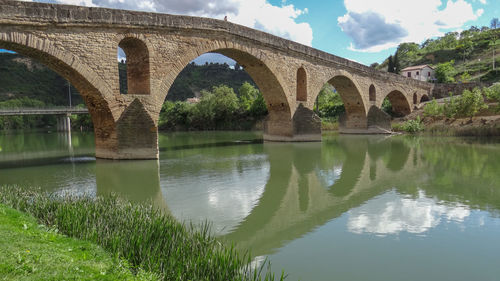 Arch bridge over river against sky